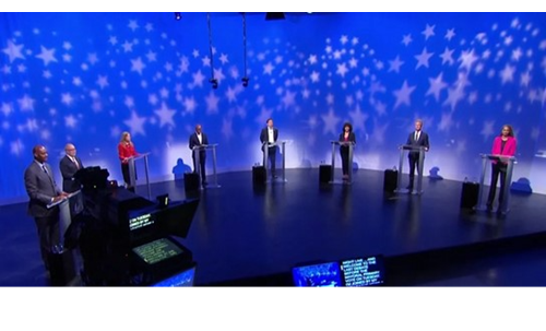 Panelists stand on a stage ahead of a previous debate cycle.